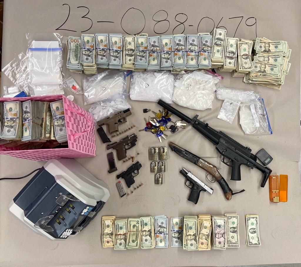Photo of seized evidence including weapons, drugs, electronic money counter, ammunition and cash